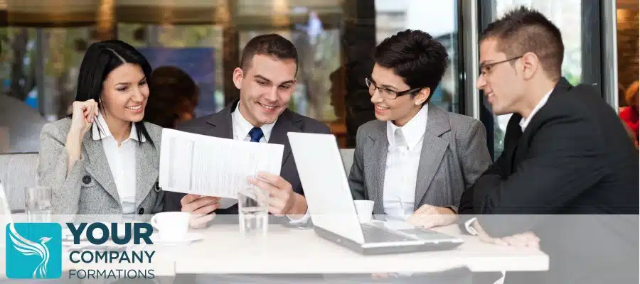 Four professionals in business suits reviewing documents and laptop for Advantages and Disadvantages of Limited Company Formation article