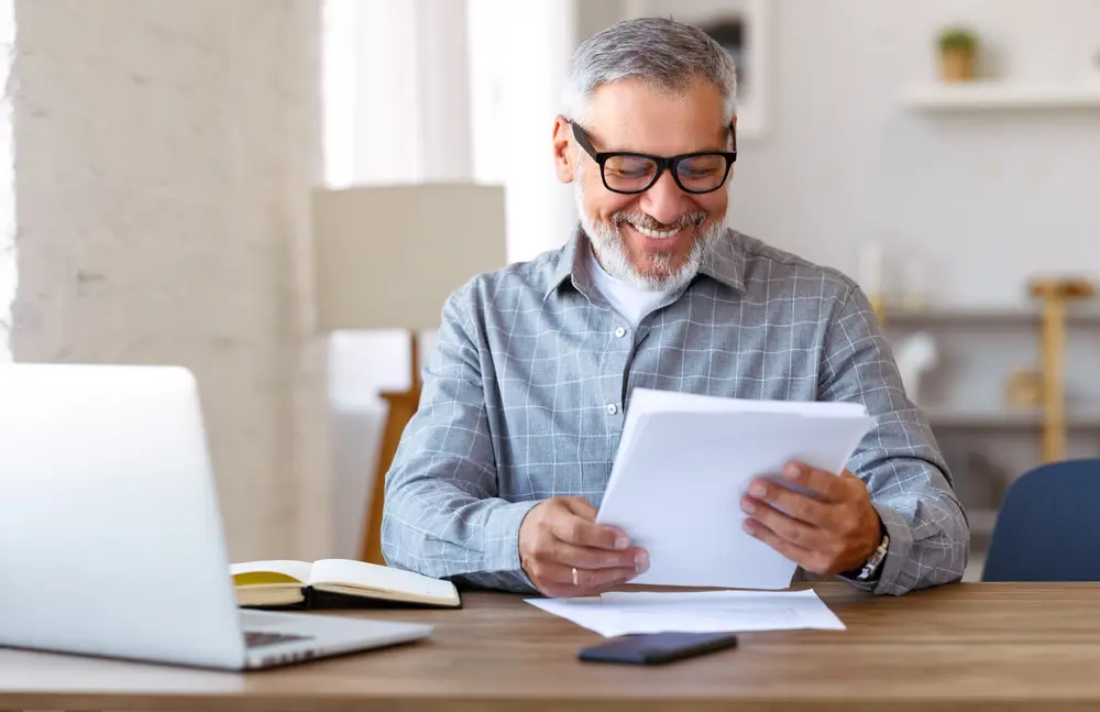 Smiling man with glasses reading a document, reviewing a limited company articles of association