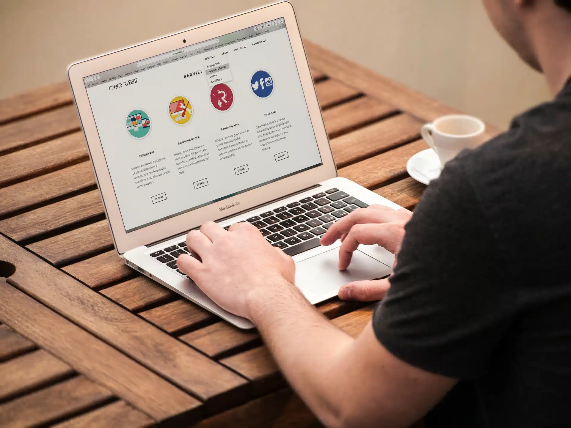 Person typing on laptop at wooden table with coffee, screen showing icons and options for company name reservation process
