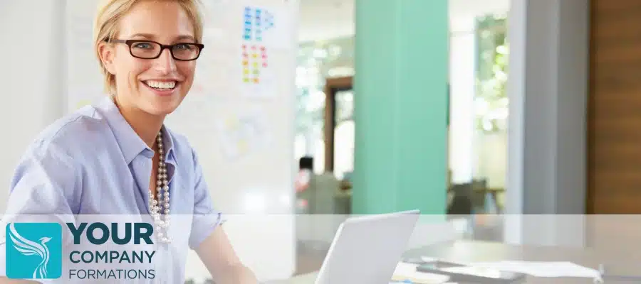 Woman with glasses smiling with laptop on desk in office, illustrating Do I Need to Inform HMRC That I Have Formed a New Limited Company