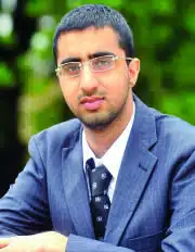 Man in suit with glasses sitting outdoors, illustrating Do We Still Believe in the Thought That Counts article concept