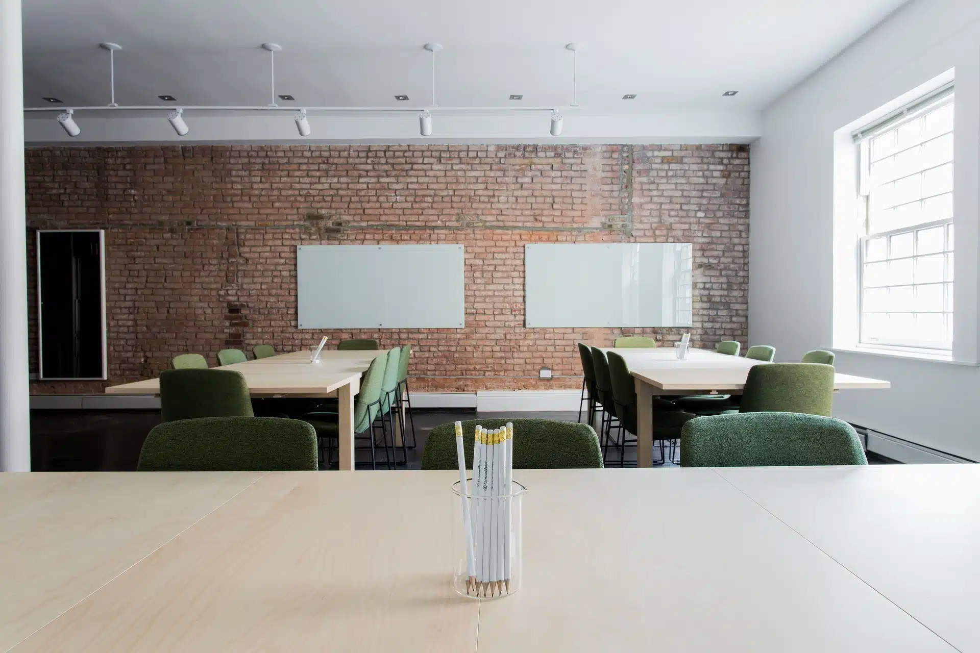 Empty modern meeting room with wooden tables, green chairs, and whiteboards against an exposed brick wall, representing an inactive dormant company with no trading activity or business operations.