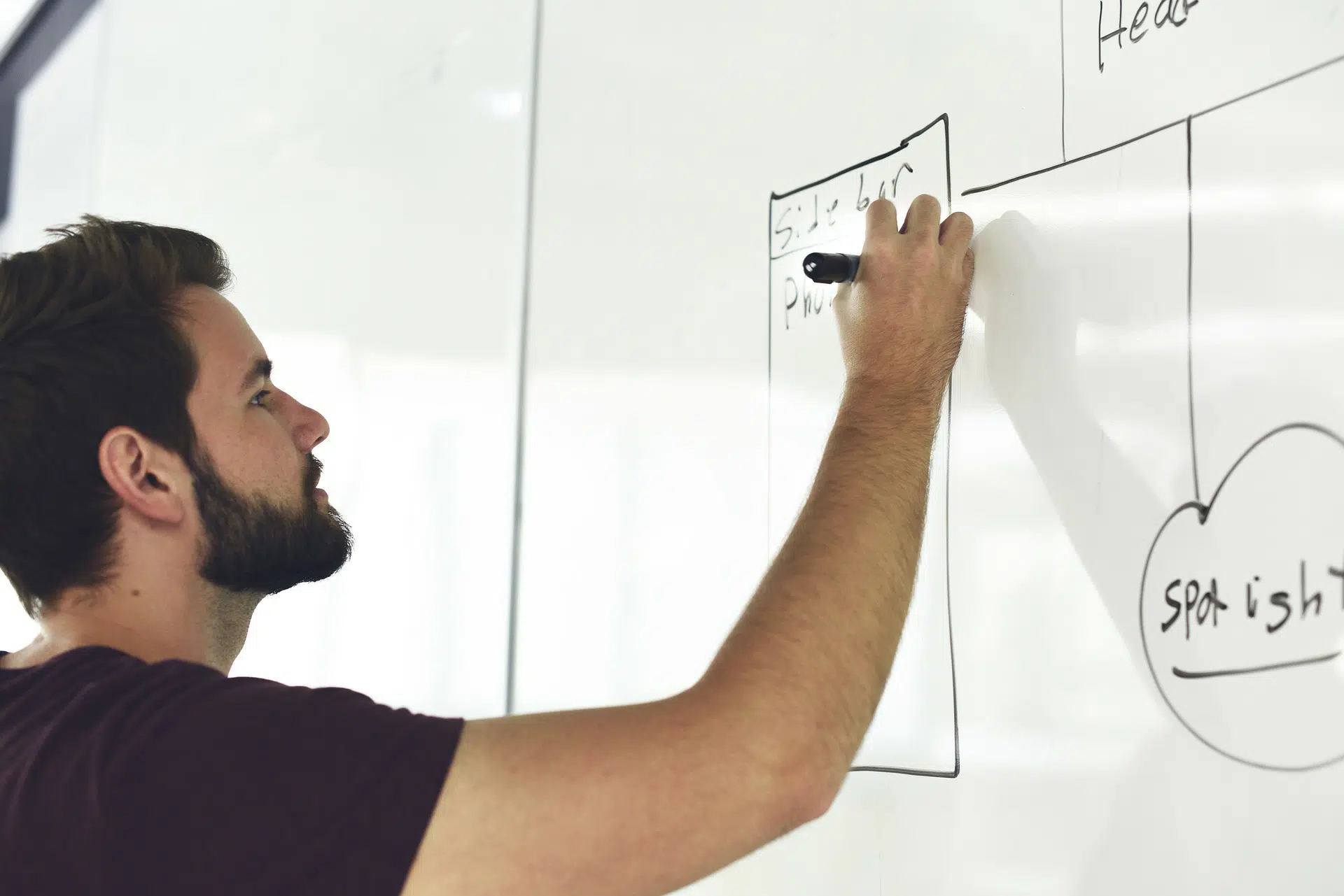 Man writing business ideas and diagrams on whiteboard for finding your perfect small business niche article