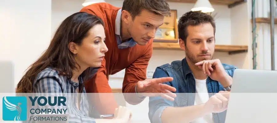 Three colleagues discussing laptop at desk for Guidance on Limited Company Meetings and Resolutions article