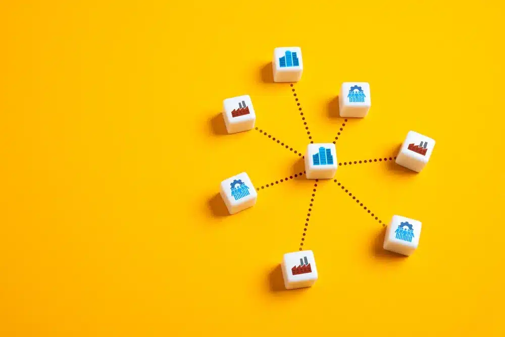 Dice showing business icons connected by dotted lines on a yellow background representing a holding company structure with multiple subsidiary companies