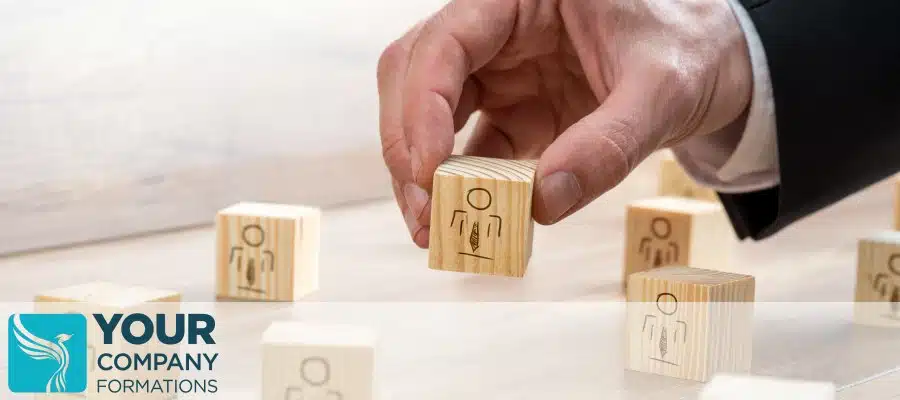 Hand placing wooden block figures on the table for How Many Shares Do I Need to Issue at Time of Company Formation article