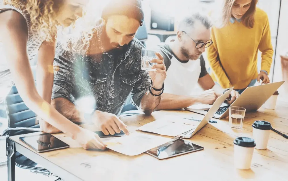 A team of entrepreneurs collaborating on laptops and documents, planning how to register a UK company