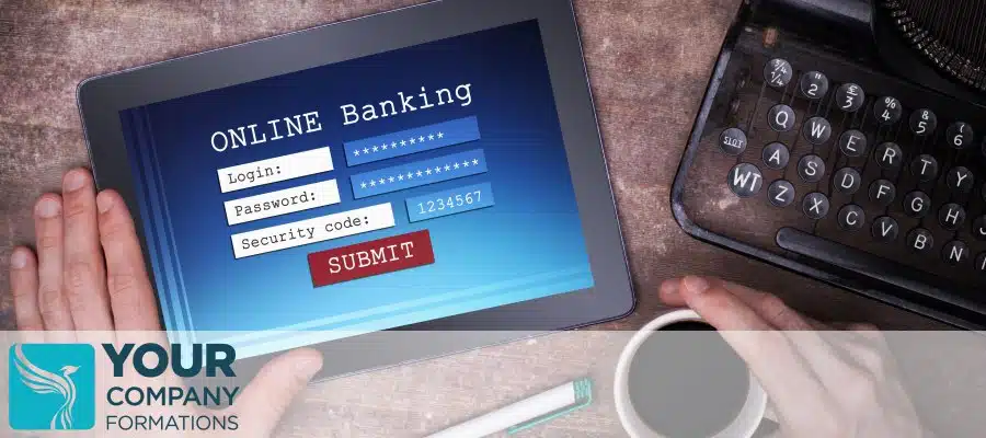 Hands holding coffee and tablet showing online banking login beside typewriter for How to Take Money Out of a Limited Company article