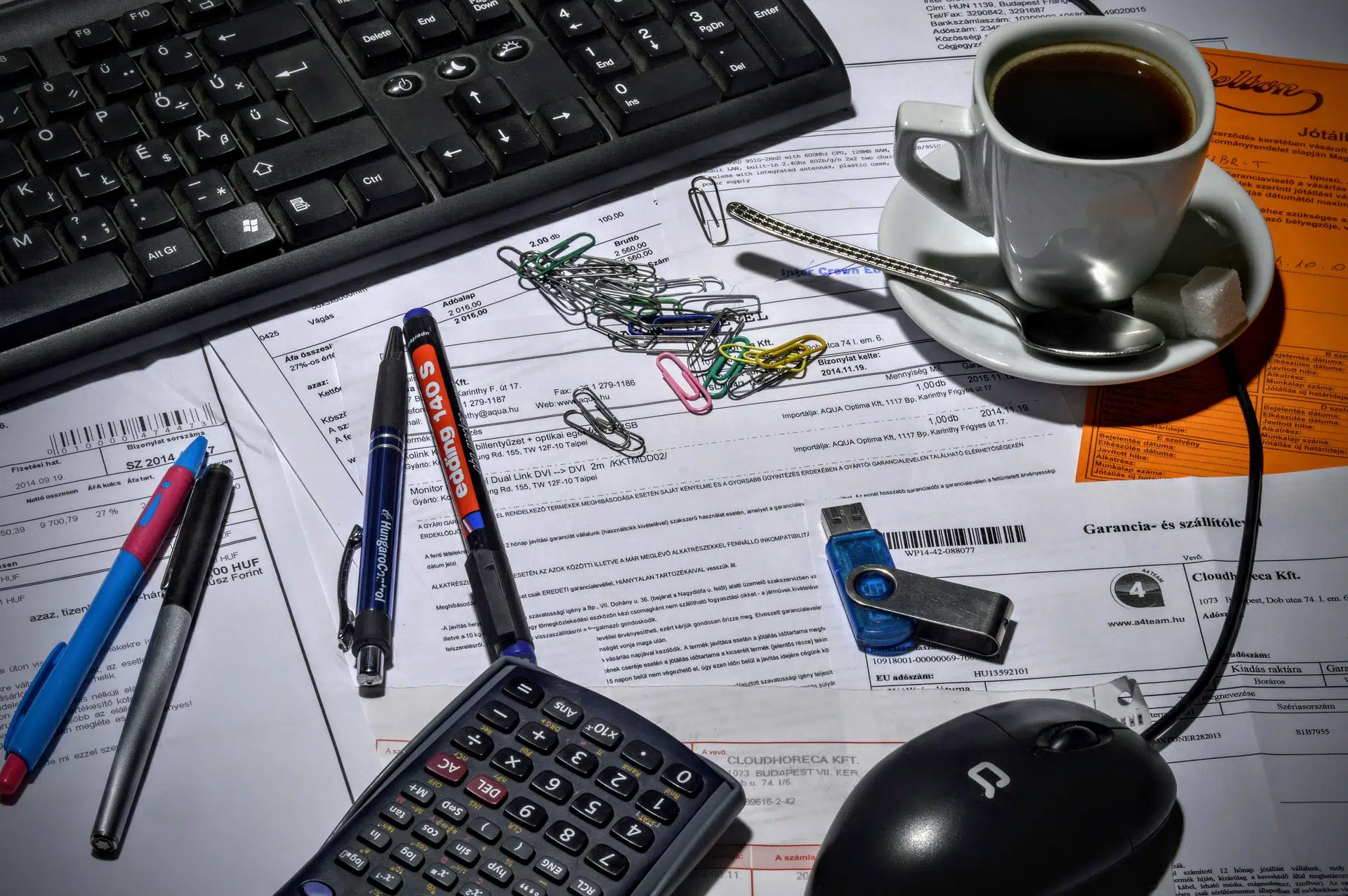 Calculator, keyboard, coffee cup, pens and clips on invoices for New Business Processes – How to Bill Customers article
