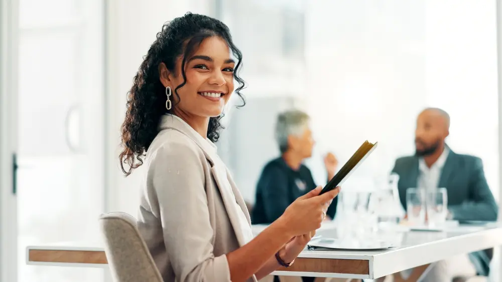 Smiling professional woman holding a tablet in a meeting room, representing personal tax account management