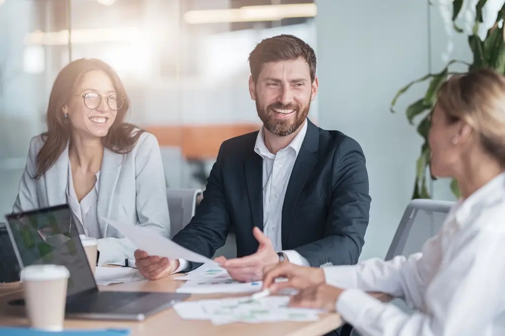 Business professionals smiling in a meeting representing the responsibilities and role of a company director in a UK limited company