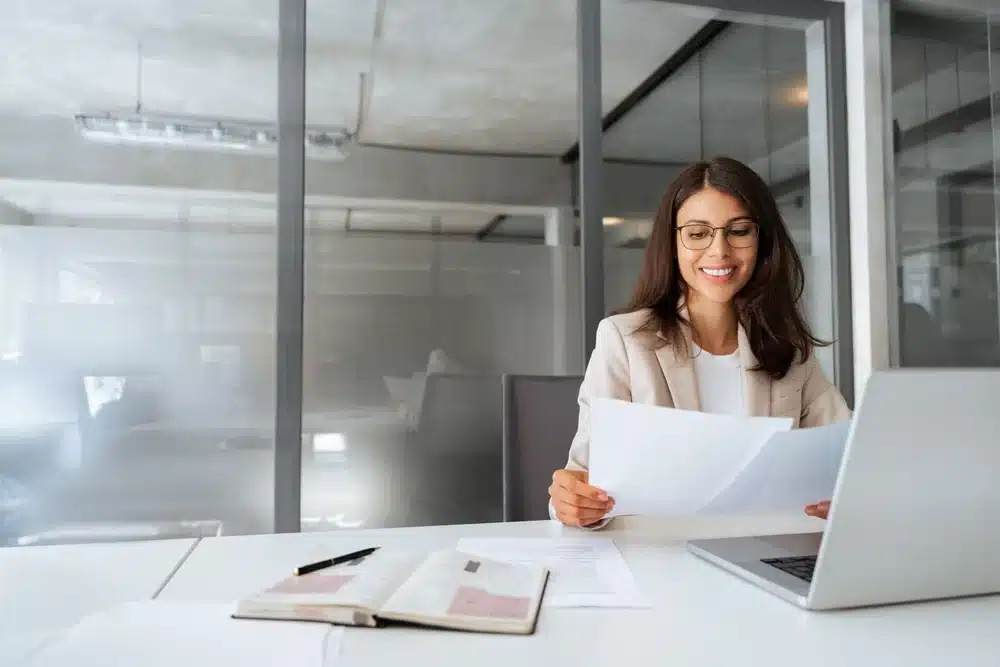 Businesswoman reviewing documents at a desk in an office while looking up her tax identification number
