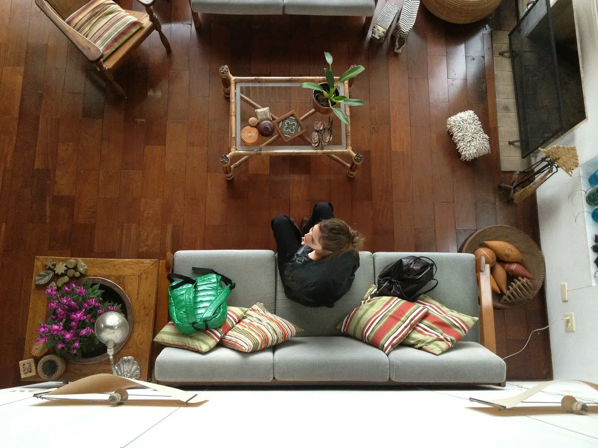 Top view of person sitting on a sofa in a living room with bags and decor for house sitting business guide