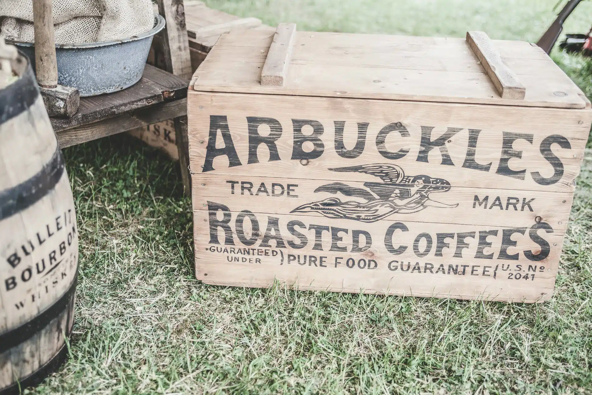 Wooden crate and barrel with printed texts, with a rustic shelf and metal basin on grass for trademark article